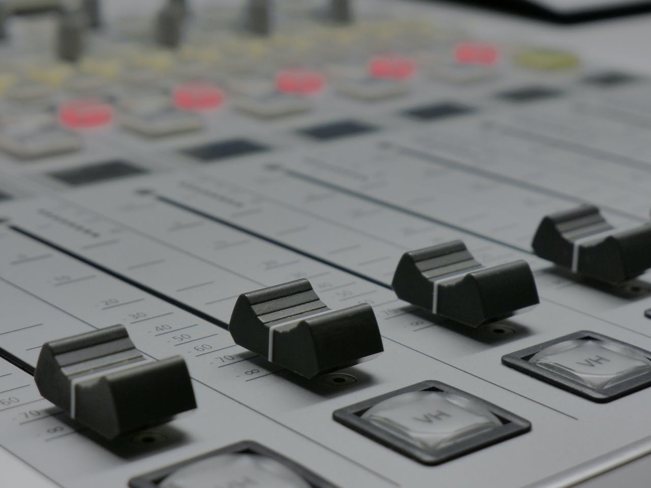 about-01 Detailed view of audio mixer sliders in a recording studio setting.